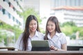 Two young Asian girls students are consulting together and using a tablet to search information for a study report Royalty Free Stock Photo