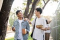 Two young Asian male best friends are enjoying talking while walking on a footpath on their campus Royalty Free Stock Photo