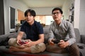 Two young men playing video games while sitting on sofa at home. Royalty Free Stock Photo