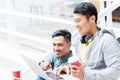 Two young Asian men using a laptop while relaxing during break Royalty Free Stock Photo