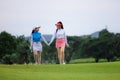 Two young asian professional golfers walking hand in hand and talk about like friend and smiling happily on the golf course,.Two Royalty Free Stock Photo