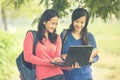 Two young Asian students standing together, one holding a laptop Royalty Free Stock Photo