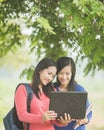 Two young Asian students standing together, one holding a laptop Royalty Free Stock Photo