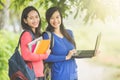 Two young Asian students standing together, one holding a laptop Royalty Free Stock Photo