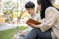 Two young Asian university students are preparing for an exam together in the university park Royalty Free Stock Photo