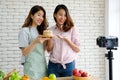 Two young asian woman food bloggers talking while recording video, vlog concept, people and technology communication