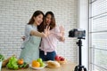 Two young asian woman food bloggers talking while recording video, vlog concept, people and technology communication