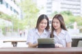 Two young Asian woman students are consulting together and using a tablet to search information for a study report Royalty Free Stock Photo