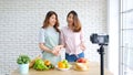 Two young asian women food bloggers talking while recording video with happy moment, vlog concept, people and technology