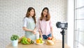 Two young asian women food bloggers talking while recording video with happy moment, vlog concept, people and technology