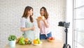 Two young asian women food bloggers talking while recording video with happy moment, vlog concept, people and technology