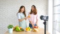 Two young asian women food bloggers talking while recording video with happy moment, vlog concept, people and technology