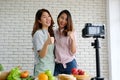 Two young asian woman food bloggers talking while recording video, vlog concept, people and technology communication