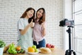 Two young asian woman food bloggers talking and thumb up while recording video, vlog concept, people, food and technology