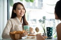 Two young Asian women friends talking at a coffee shop. Royalty Free Stock Photo