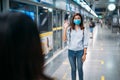 Two young asian women friends wearing protective mask meet in a subway station with bare hands. Instead of greeting with a hug or