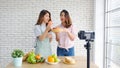 Two young asian women healthy food bloggers talking while recording video with happy moment, vlog concept, people and technology