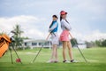 Two young asian women professional golfers stand and pose looking at camera and smiling taking photo at the golf course Royalty Free Stock Photo