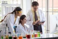 Two young asian woman research scientist and senior man supervisor preparing test tube and analyzing microscope With Computer in