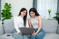 Two young asian women shopping online shopping on laptop while sitting on sofa together in living room Royalty Free Stock Photo