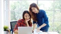 Two young asian women working with laptop computer at home office with happy emotion moment, working at home, small business,