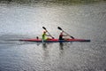 Two young athletes are sailing canoe on river, controlling oars. Active outdoor sports training. Side view. Copy space.