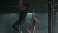 Two young athletic people dowing pull-ups on rope climbing together in spacious gym. 4K slow motion