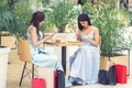 Two caucasian women are looking to cell phone at cafe after shopping outdoors. Royalty Free Stock Photo