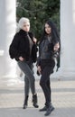 Two young attractive women in dark autumn clothes in a public Park