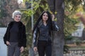 Two young attractive women in dark autumn clothes walk along park