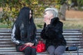 Two young attractive women sitting on bench in park and talking