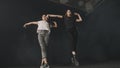 Two young attractive women training a synchronous dance choreography in dark studio