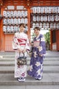 Two young and beautiful Asian women looking at the camera, holding hand bag and wearing Yukata.