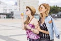 Two young beautiful blonde hipster girls on summer day having fun in european city blowing bubbles. Copy space Royalty Free Stock Photo