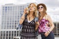 Two young beautiful blonde hipster girls on summer day having fun in european city blowing bubbles. Copy space Royalty Free Stock Photo