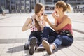 Two young beautiful blonde hipster girls on summer day having fun in european city. Eating doughnut. Copy space Royalty Free Stock Photo