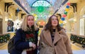 Two young beautiful female friends at the shopping mall smiling, admire the bright Christmas decor Royalty Free Stock Photo