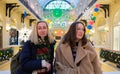 Two young beautiful female friends at the shopping mall smiling, admire the bright Christmas decor Royalty Free Stock Photo