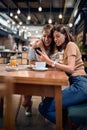 Two young beautiful girls in cafe having a great time. Woman showing something on her phone Royalty Free Stock Photo