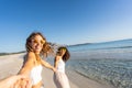 Two young beautiful girls with colorful sunglasses dress boho in summer looking at camera on the beach laughing amused for Royalty Free Stock Photo