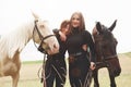 Two young beautiful girls in gear for riding near their horses. They love animals Royalty Free Stock Photo