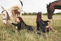 Two young beautiful girls in gear for riding near their horses. They love animals Royalty Free Stock Photo