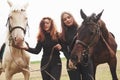 Two young beautiful girls in gear for riding near their horses. They love animals Royalty Free Stock Photo