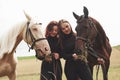 Two young beautiful girls in gear for riding near their horses. They love animals Royalty Free Stock Photo