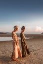 Two young beautiful girls in turban walking on the beach at sunset Royalty Free Stock Photo