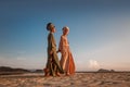 Two young beautiful girls in turban walking on the beach at sunset Royalty Free Stock Photo