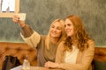 Two young beautiful girls using smart phone and making selfie in Royalty Free Stock Photo