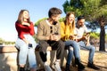 Two young beautiful heterosexual couple laughing each other using smartphone to chatting online - Happy millennial group of people