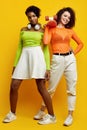 Two young beautiful hipster girls in trendy colorful summer clothes Royalty Free Stock Photo