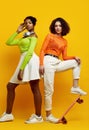 Two young beautiful hipster girls in trendy colorful summer clothes Royalty Free Stock Photo